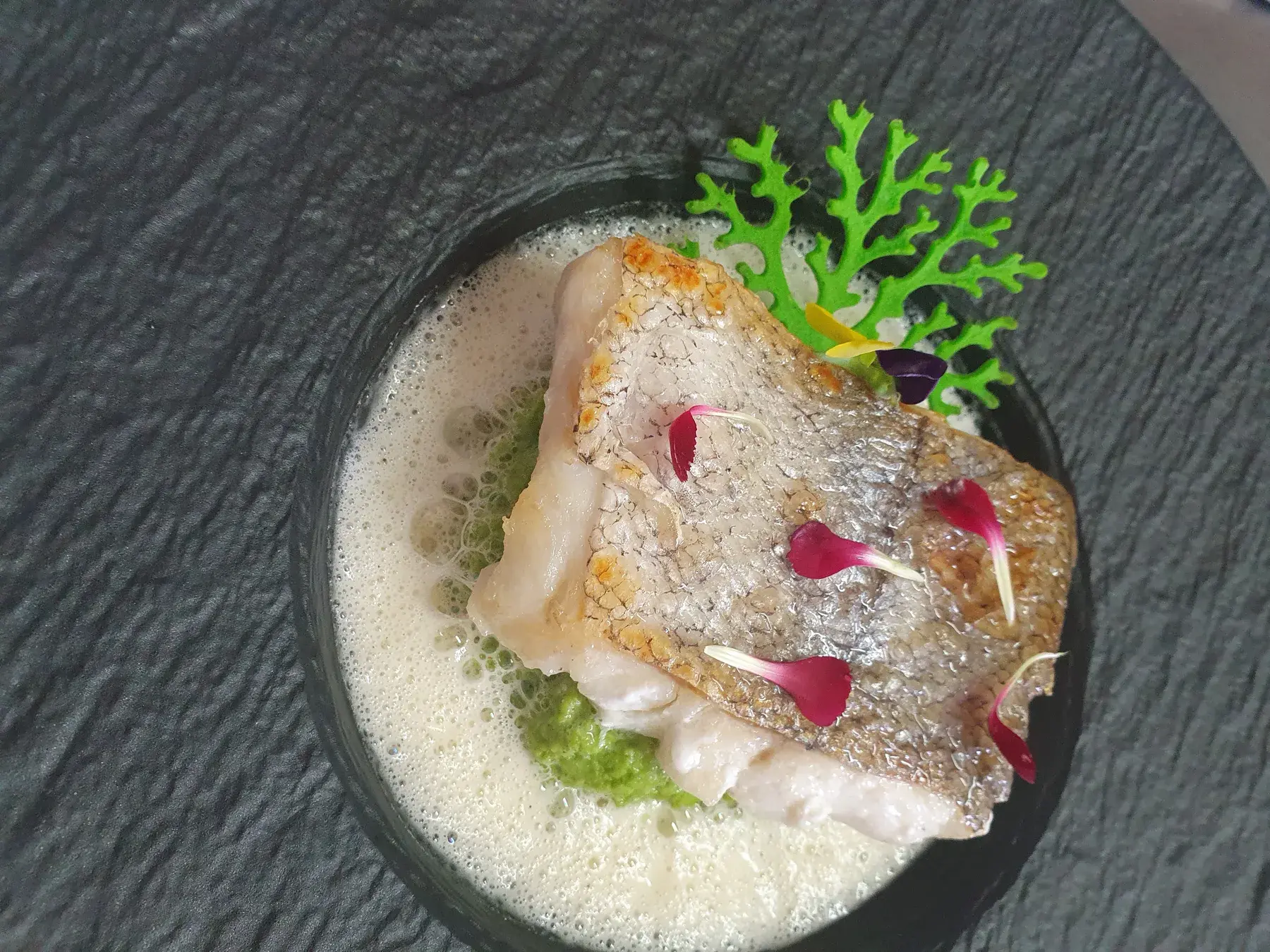 Poisson à la peau croustillante, écume légère et pétales de rose